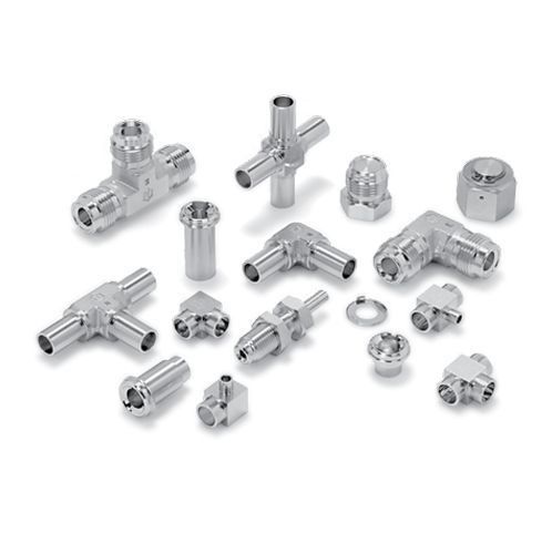 Eine Sammlung verschiedener glänzender Sanitärarmaturen aus Metall, darunter Verbindungsstücke, Bögen und Ventile, die ordentlich auf einer Fläche angeordnet sind.